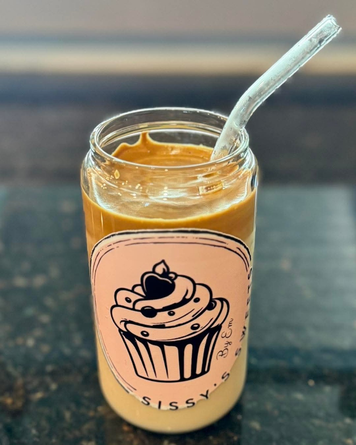Sissy's Sweets by Em branded glass cup with caramel coffee drink and glass straw