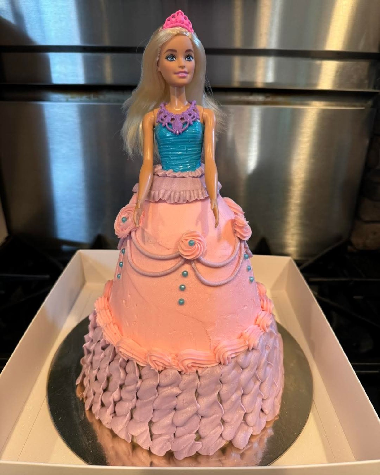 Barbie doll dress cake in pink and lavender frosting with ruffles and rose details