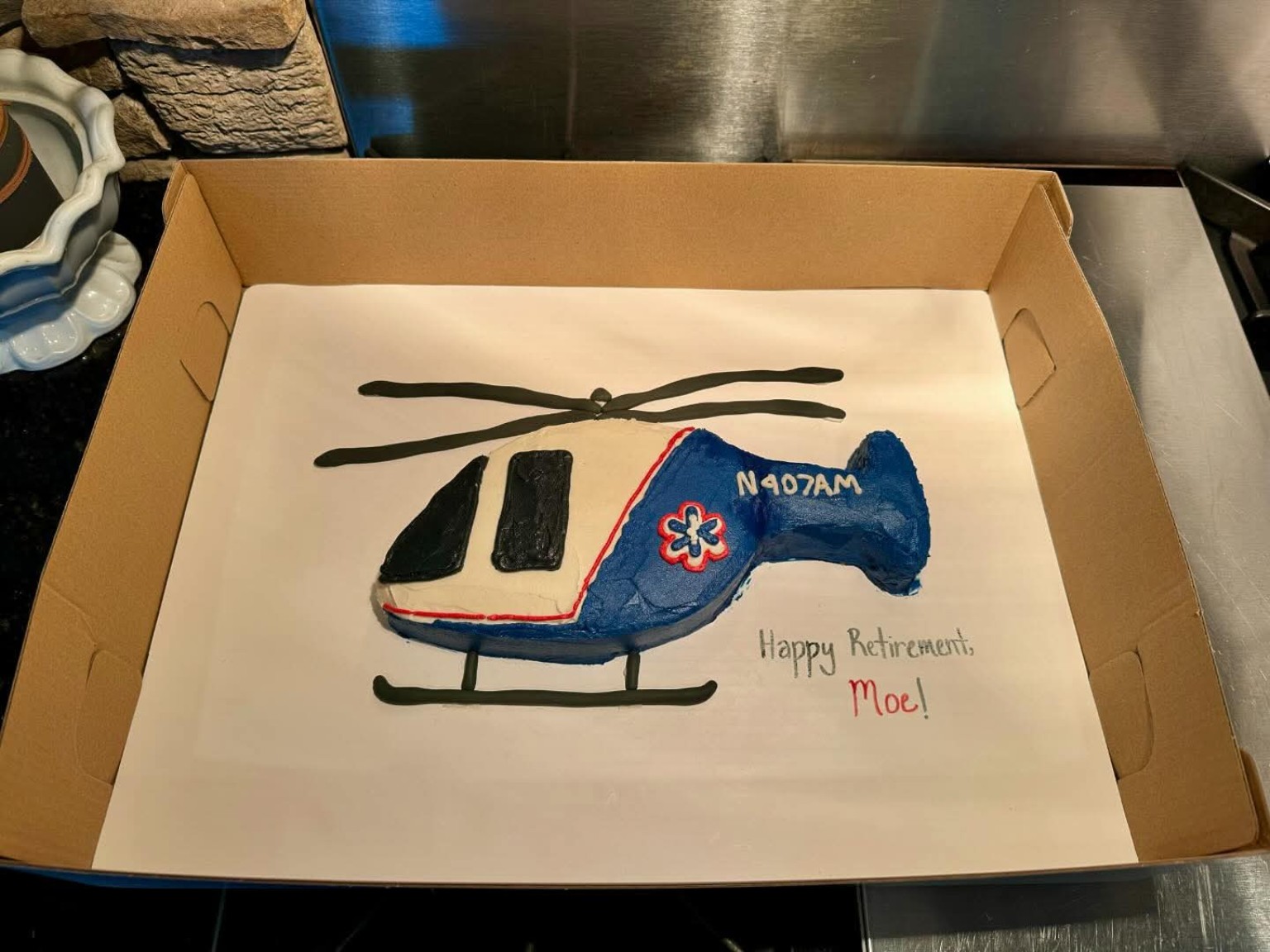 Custom shaped helicopter cake reading Happy Retirement Moe with emergency medical service markings
