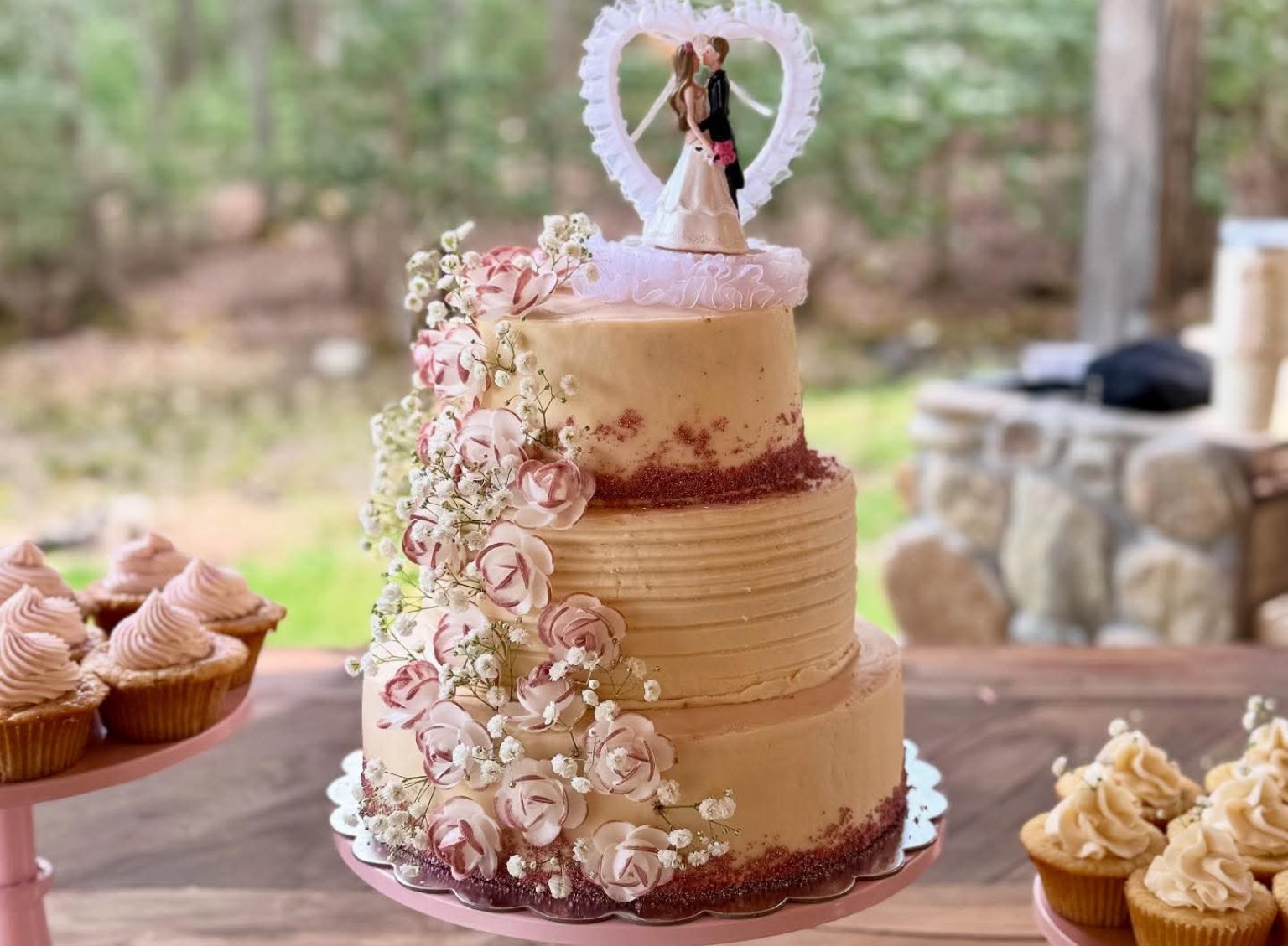 2-tier wedding cake with cascading blush roses, baby's breath, and a bride and groom topper