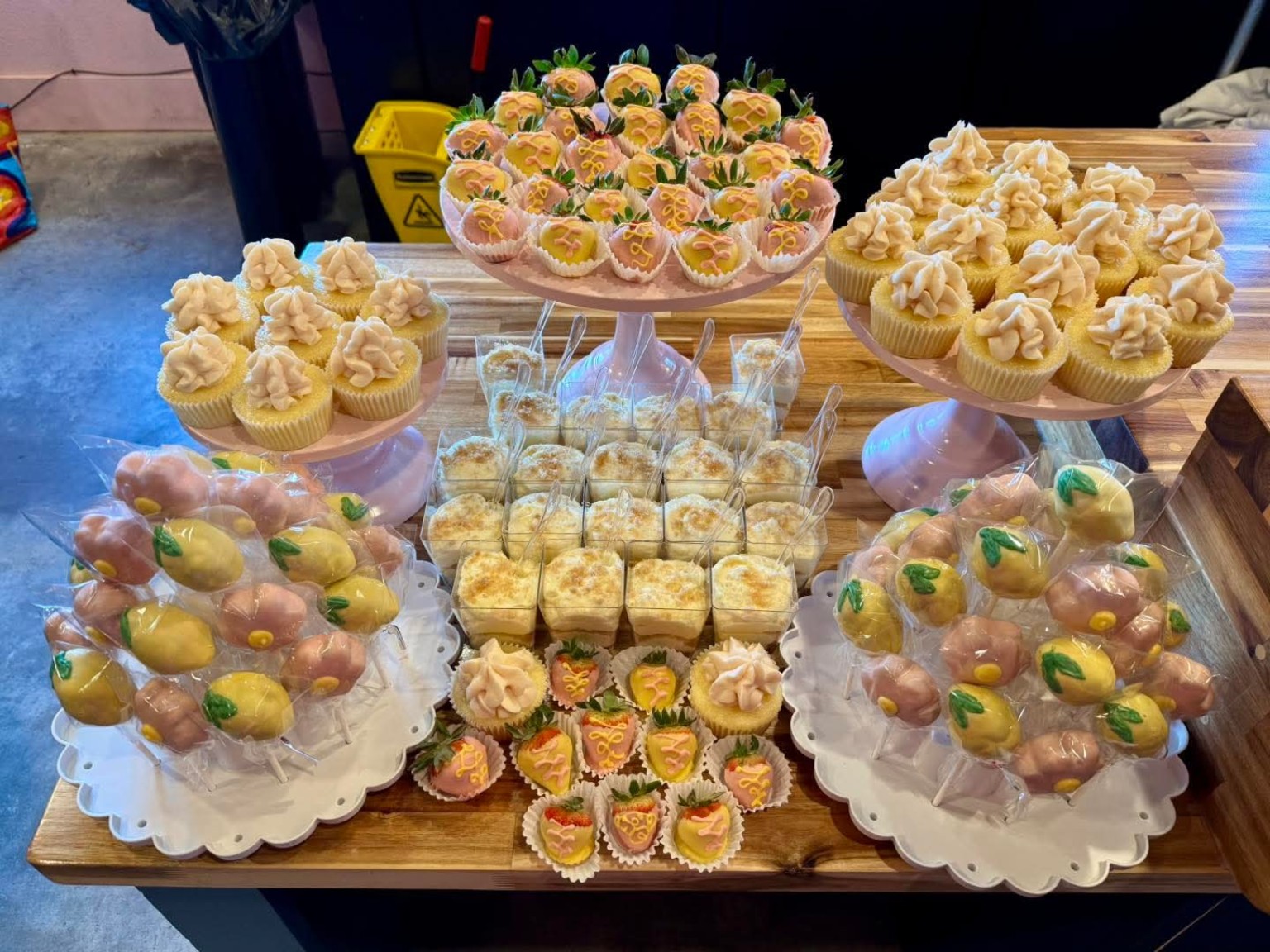 Full dessert table spread with cupcakes, pudding cups, cake pops, and chocolate strawberries